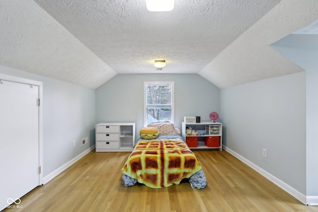 5945 Mcfarland Rd, Indianapolis, IN 46227 - bedroom featuring baseboards, vaulted ceiling, wood finished floors, and a textured ceiling