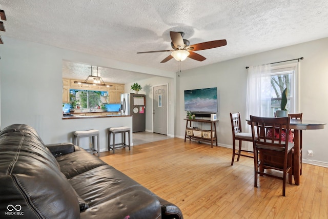 5945 Mcfarland Rd, Indianapolis, IN 46227 - living area featuring baseboards, light wood-style flooring, a textured ceiling, and a ceiling fan