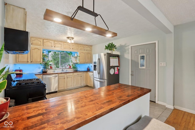 5945 Mcfarland Rd, Indianapolis, IN 46227 - kitchen with a textured ceiling, light tile patterned flooring, butcher block counters, appliances with stainless steel finishes, and a sink