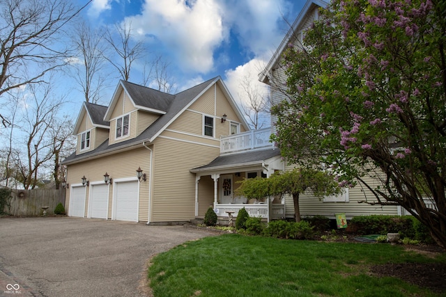 313 E Wabash Ave, Crawfordsville, IN 47933 - view of front of house featuring a balcony, a front lawn, aphalt driveway, a garage, and covered porch