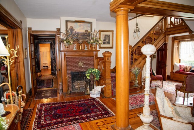 313 E Wabash Ave, Crawfordsville, IN 47933 - living area with stairs, a brick fireplace, ornate columns, and wood finished floors