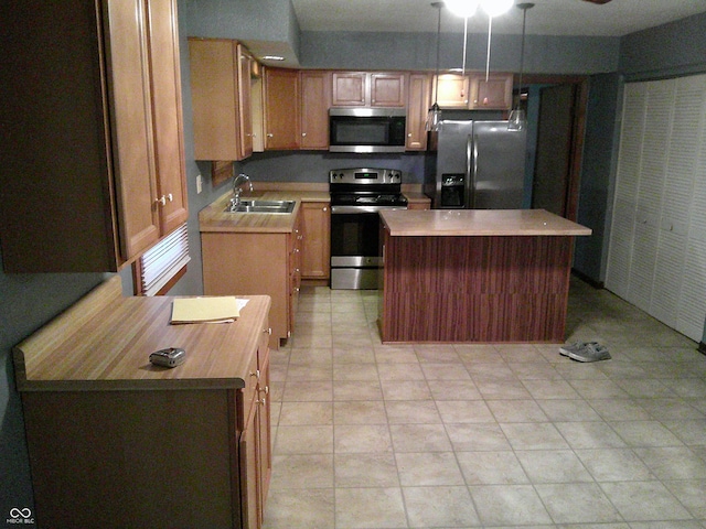 kitchen with a center island, light tile patterned flooring, stainless steel appliances, pendant lighting, and a sink