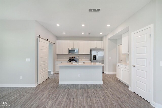 1268 Newton St, Avon, IN 46123 - kitchen with a barn door, baseboards, visible vents, stainless steel appliances, and light wood-type flooring