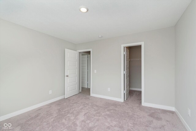 1268 Newton St, Avon, IN 46123 - unfurnished bedroom with a walk in closet, light carpet, baseboards, and a closet