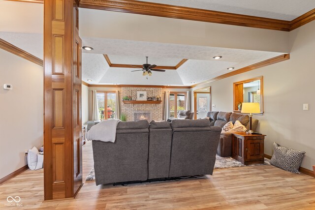 8095 Christopher Ct, Avon, IN 46123 - living room with a tray ceiling, light wood-style floors, ceiling fan, crown molding, and a fireplace