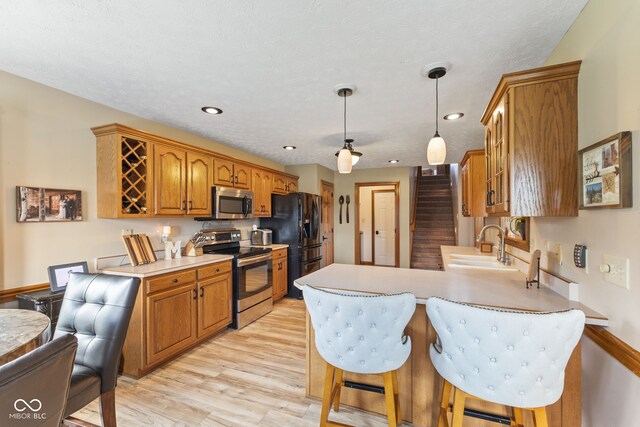 8095 Christopher Ct, Avon, IN 46123 - kitchen with a sink, brown cabinetry, light countertops, a peninsula, and appliances with stainless steel finishes