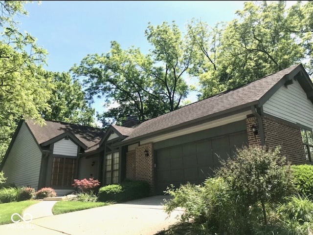 ranch-style house with brick siding, an attached garage, a shingled roof, and concrete driveway