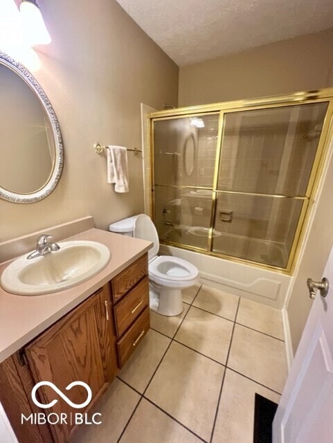 full bathroom with combined bath / shower with glass door, toilet, a textured ceiling, vanity, and tile patterned flooring