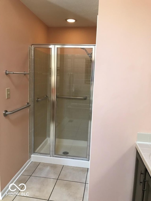 bathroom with tile patterned floors, vanity, baseboards, and a stall shower