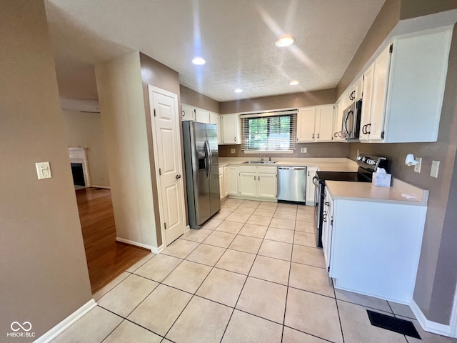 kitchen featuring baseboards, light countertops, white cabinetry, appliances with stainless steel finishes, and a sink