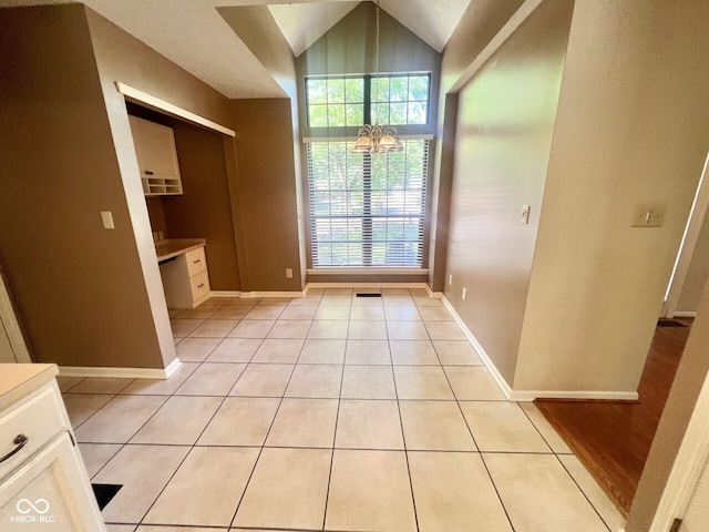 unfurnished dining area featuring a chandelier, light tile patterned flooring, baseboards, and vaulted ceiling