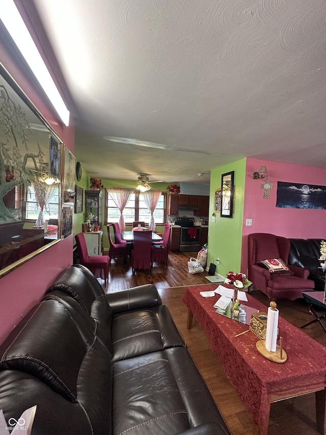 living area featuring dark wood-type flooring, a textured ceiling, and a ceiling fan