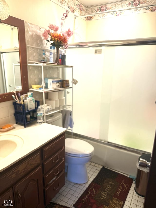 full bath featuring combined bath / shower with glass door, tile patterned flooring, vanity, and toilet