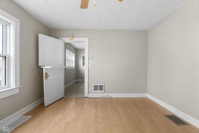 5713 Bluff Rd, Indianapolis, IN 46217 - spare room with visible vents, a ceiling fan, light wood-style floors, and a healthy amount of sunlight
