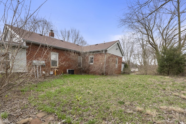 5713 Bluff Rd, Indianapolis, IN 46217 - view of property exterior featuring a yard, brick siding, central AC, and a chimney
