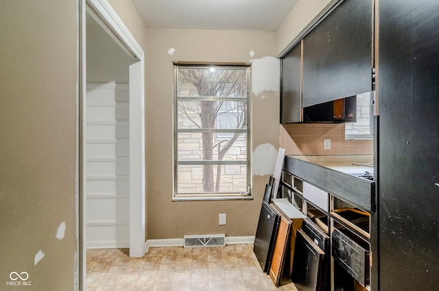 kitchen with plenty of natural light, visible vents, baseboards, and decorative backsplash