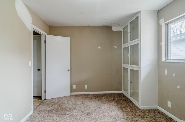 carpeted spare room featuring baseboards