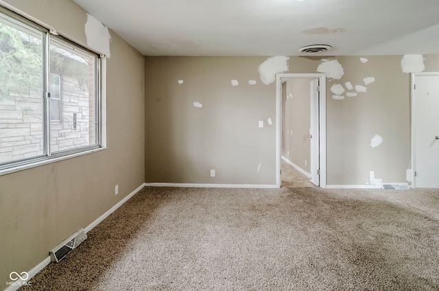 carpeted empty room featuring baseboards and visible vents
