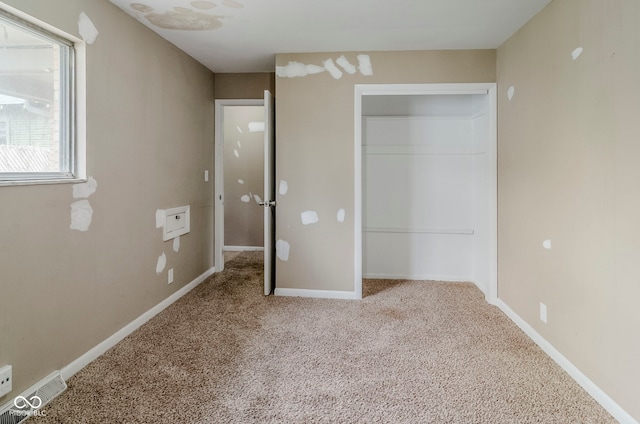 unfurnished bedroom featuring baseboards, carpet floors, visible vents, and a closet