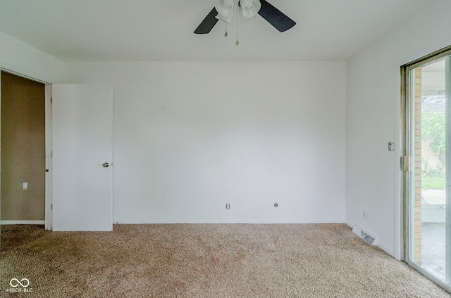 empty room featuring visible vents, carpet flooring, and ceiling fan