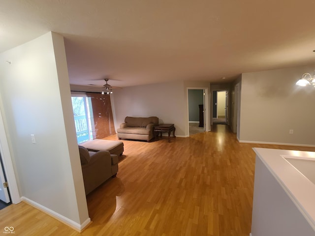 6525 Emerald Hill Ct Unit 208, Indianapolis, IN 46237 - living room with baseboards, ceiling fan with notable chandelier, and light wood-style flooring