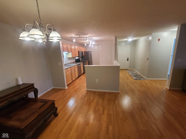 6525 Emerald Hill Ct Unit 208, Indianapolis, IN 46237 - kitchen featuring a sink, baseboards, a chandelier, light wood-style floors, and appliances with stainless steel finishes