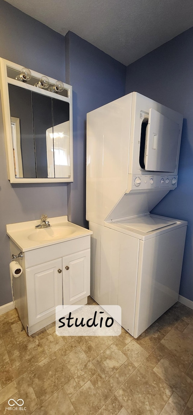 403 S Mill St, Veedersburg, IN 47987 - clothes washing area featuring stacked washer and dryer, stone finish flooring, a sink, baseboards, and cabinet space
