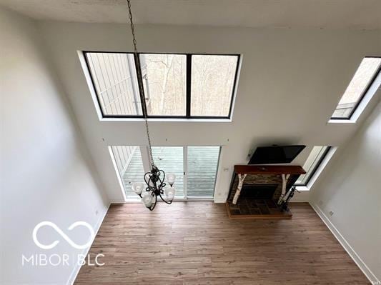 unfurnished living room featuring baseboards, plenty of natural light, a notable chandelier, and wood finished floors