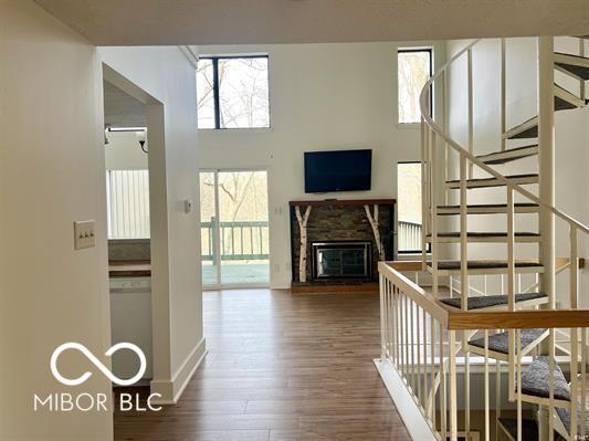 interior space with wood finished floors, baseboards, a glass covered fireplace, and stairway