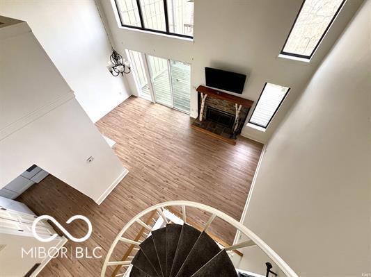 stairway featuring a stone fireplace, a high ceiling, and wood finished floors