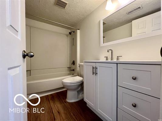 bathroom featuring vanity, visible vents, toilet, and wood finished floors
