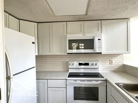 kitchen with white appliances, light countertops, backsplash, and a textured ceiling