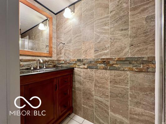 bathroom with tile patterned flooring, tile walls, and vanity