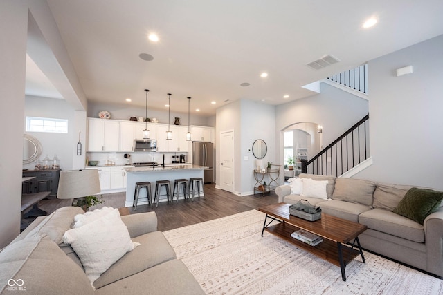 1534 Cloverdon Dr, Westfield, IN 46074 - living room with arched walkways, dark wood-style flooring, recessed lighting, stairs, and baseboards