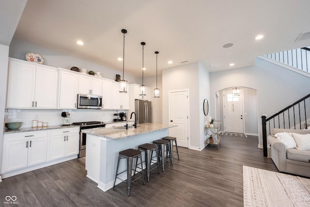 1534 Cloverdon Dr, Westfield, IN 46074 - kitchen featuring stainless steel appliances, arched walkways, dark wood-type flooring, a kitchen island with sink, and a sink
