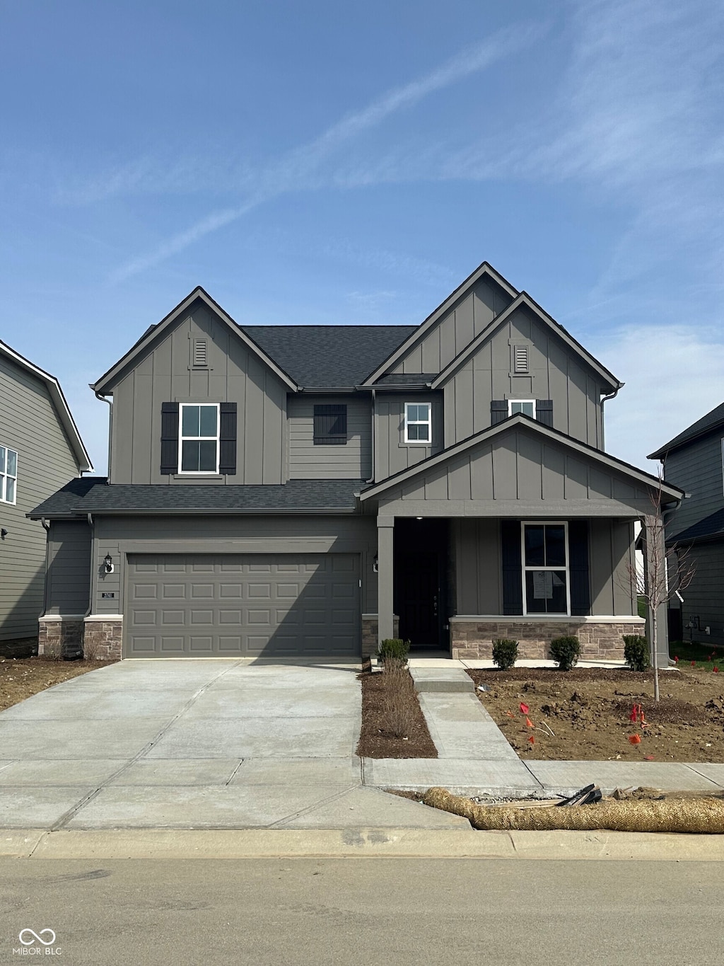 view of front of house featuring concrete driveway, roof with shingles, board and batten siding, stone siding, and a garage