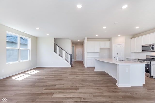 2741 Penn Ave, Plainfield, IN 46168 - kitchen with stainless steel appliances, recessed lighting, a kitchen island with sink, light wood-type flooring, and white cabinetry
