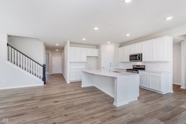 2741 Penn Ave, Plainfield, IN 46168 - kitchen with appliances with stainless steel finishes, light wood-style flooring, a center island with sink, white cabinetry, and recessed lighting