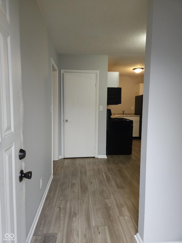 1931 Brentwood Dr, Anderson, IN 46011 - hallway featuring light wood-style flooring, a textured ceiling, baseboards, and visible vents
