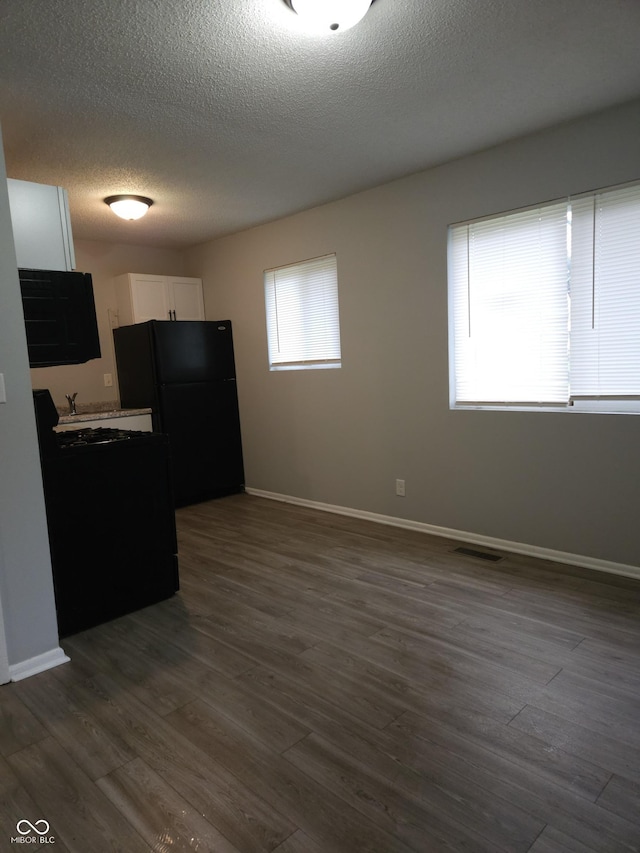 1931 Brentwood Dr, Anderson, IN 46011 - kitchen featuring a textured ceiling, freestanding refrigerator, white cabinets, visible vents, and dark wood finished floors