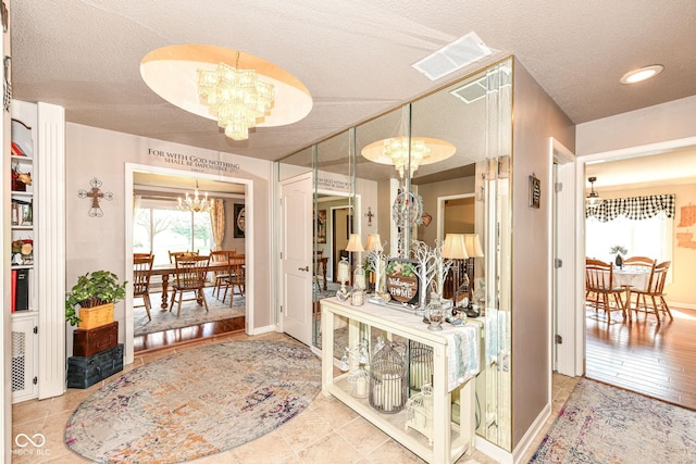 1153 Diablo Rd, Greenwood, IN 46143 - corridor featuring a chandelier, a textured ceiling, baseboards, and visible vents