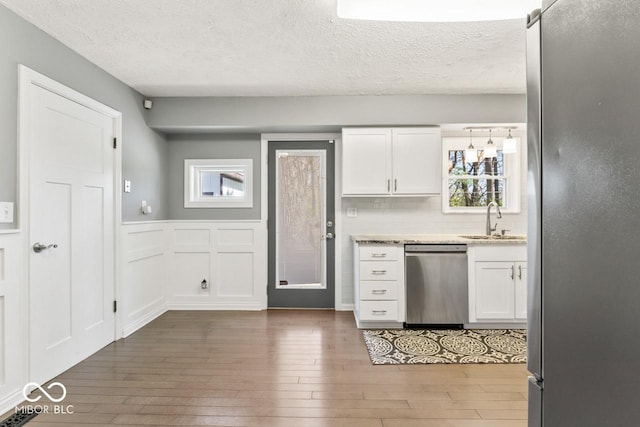 10129 Guilford Ave, Carmel, IN 46280 - kitchen featuring a sink, wood-type flooring, white cabinetry, wainscoting, and appliances with stainless steel finishes