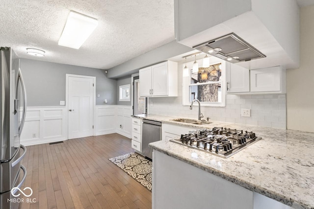 10129 Guilford Ave, Carmel, IN 46280 - kitchen with a sink, a wainscoted wall, white cabinets, appliances with stainless steel finishes, and hardwood / wood-style flooring