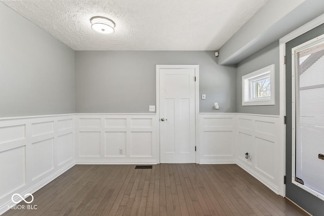 10129 Guilford Ave, Carmel, IN 46280 - unfurnished room with a textured ceiling, visible vents, a wainscoted wall, dark wood-style flooring, and a decorative wall
