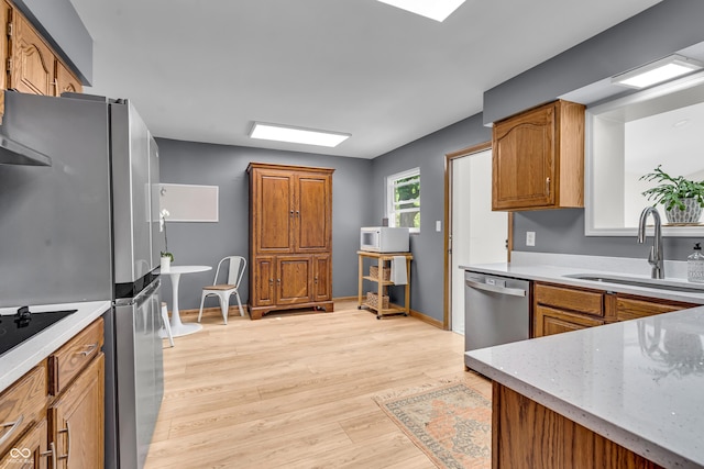 7205 Steven Ln, Indianapolis, IN 46260 - kitchen featuring appliances with stainless steel finishes, a sink, light wood finished floors, and brown cabinets