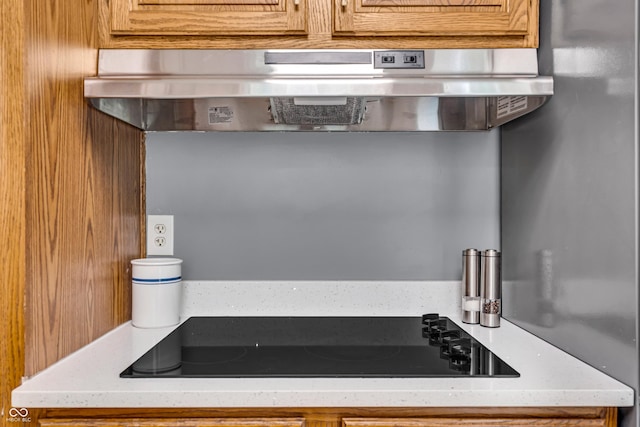 7205 Steven Ln, Indianapolis, IN 46260 - kitchen with under cabinet range hood, black electric cooktop, and brown cabinets