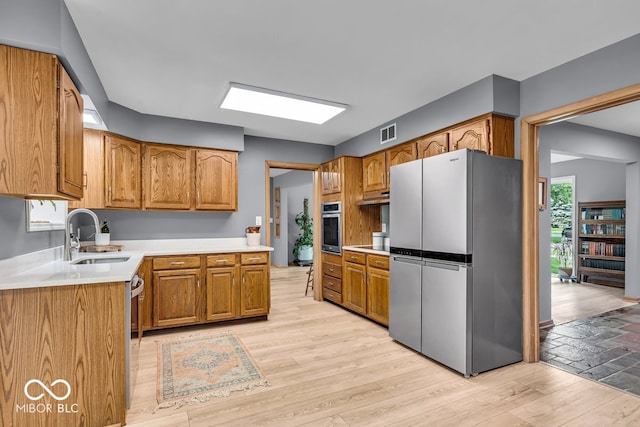 7205 Steven Ln, Indianapolis, IN 46260 - kitchen featuring appliances with stainless steel finishes, a sink, brown cabinets, and under cabinet range hood
