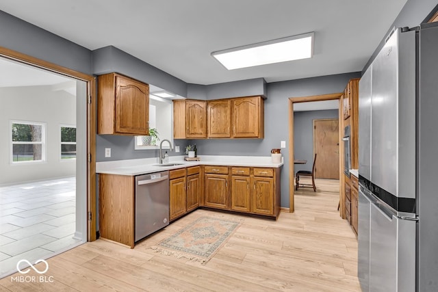 7205 Steven Ln, Indianapolis, IN 46260 - kitchen featuring stainless steel appliances, brown cabinets, a sink, light wood finished floors, and light countertops