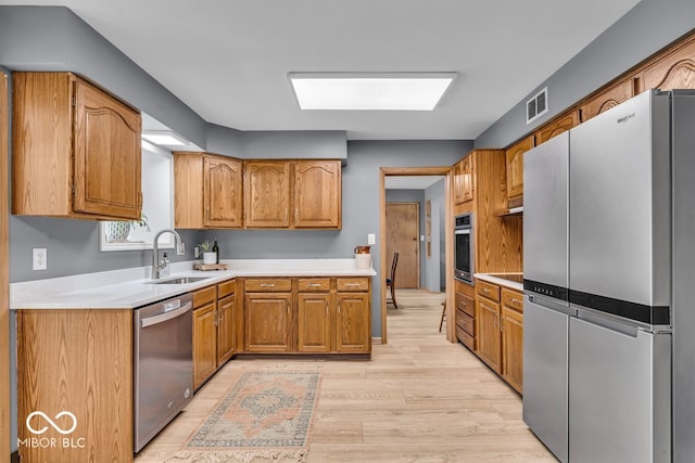 7205 Steven Ln, Indianapolis, IN 46260 - kitchen featuring appliances with stainless steel finishes, a sink, light wood-style floors, and light countertops