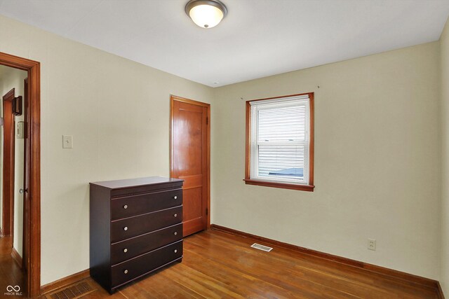 bedroom with dark wood-type flooring and baseboards